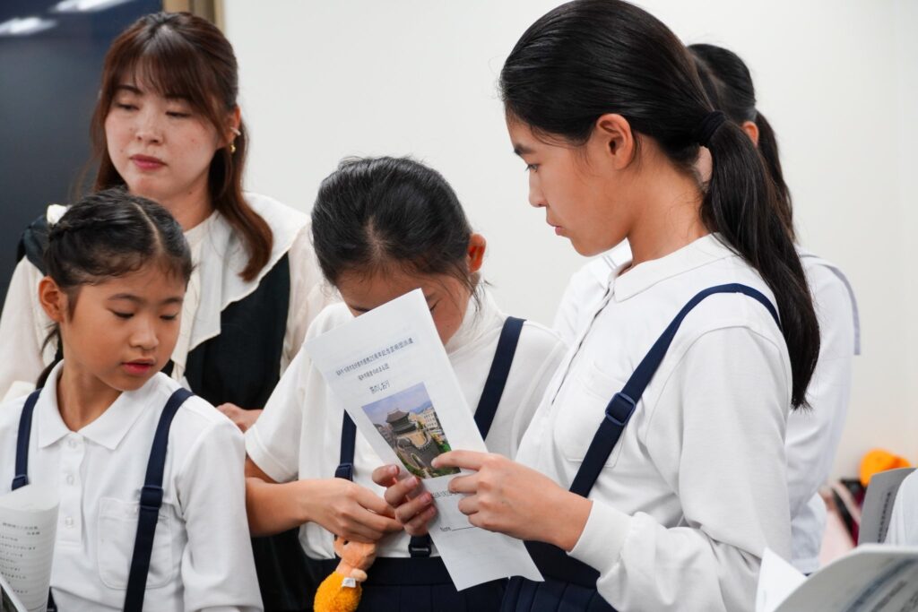 旅のしおりを受け取り、読む子どもたち