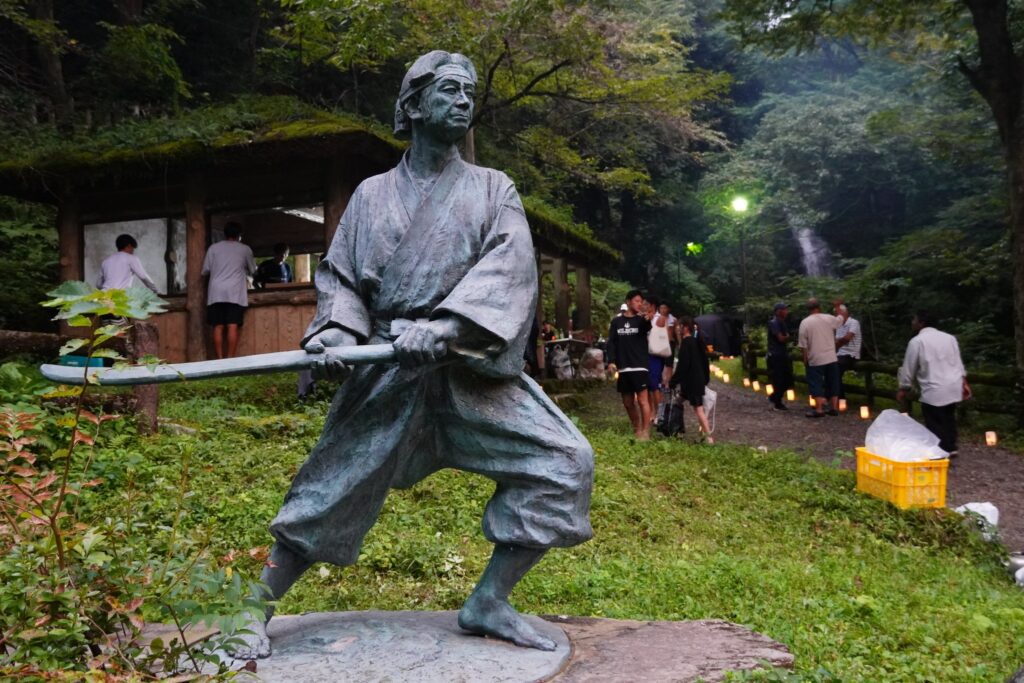 佐々木小次郎の像と、道に並ぶ灯り