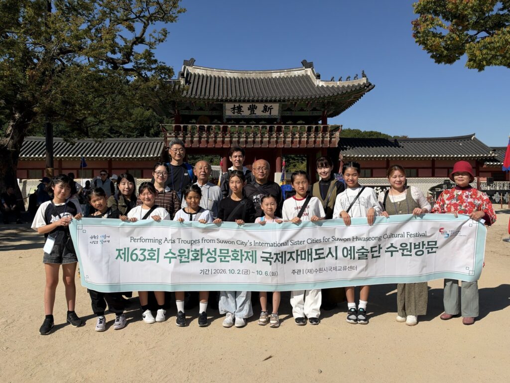 華城行宮の新豊楼の前で、横断幕を持って記念写真に並ぶ公演団